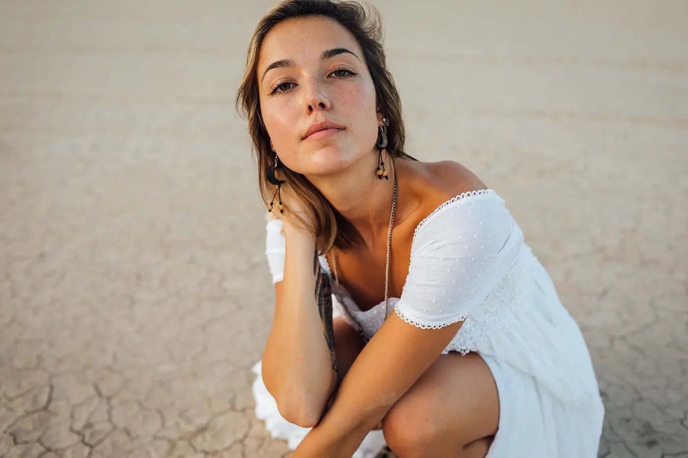 Femme en robe blanche accroupie dans le désert