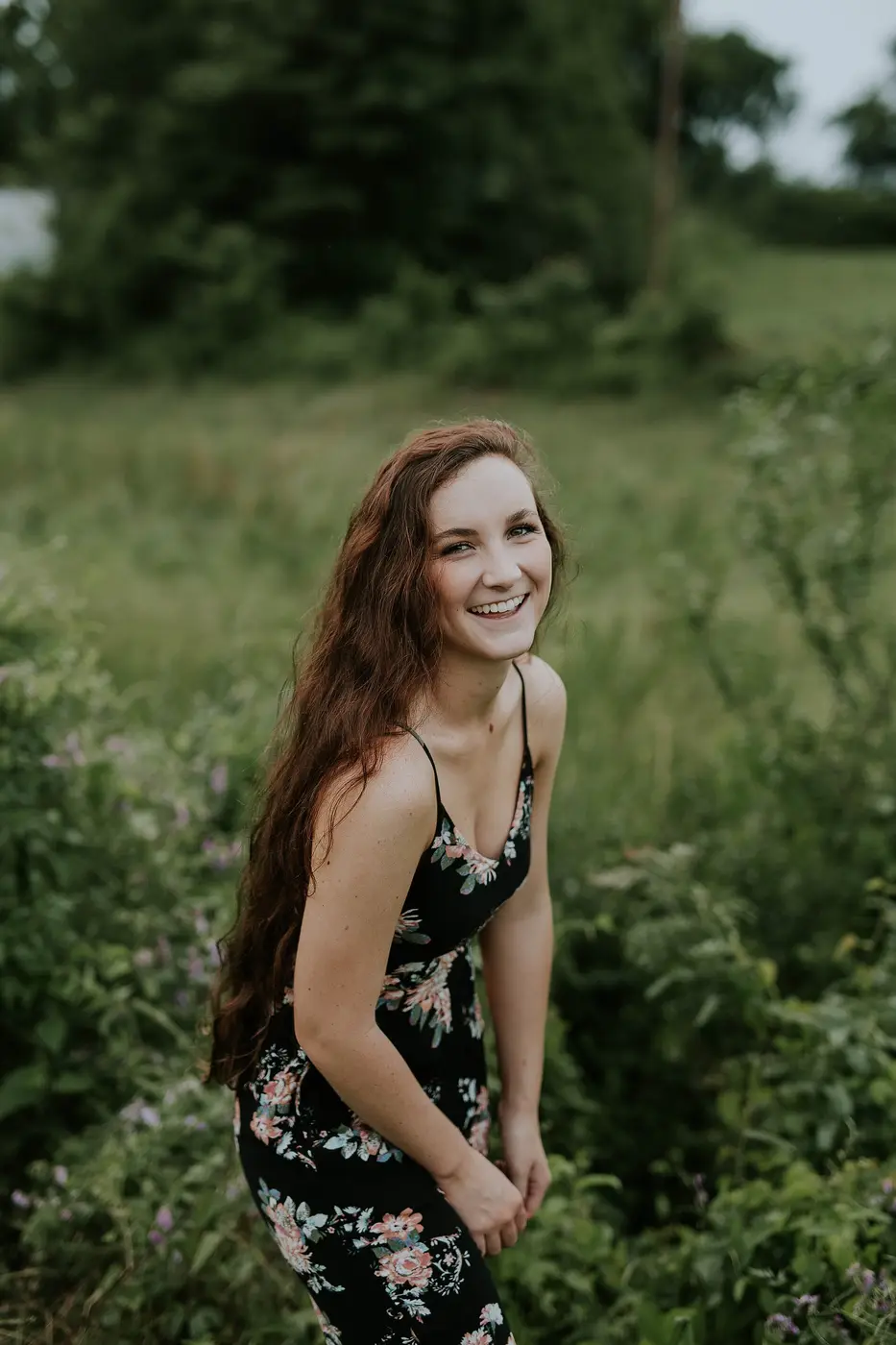 Femme souriante en robe à fleurs dans l'herbe
